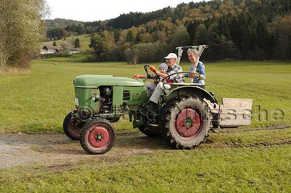 Two generations, the grandparents and the grandchild on a tractor in Bergen, a municipality in the Upper Bavarian district of Traunstein - Jrg Nitzsche Hamburg Germany